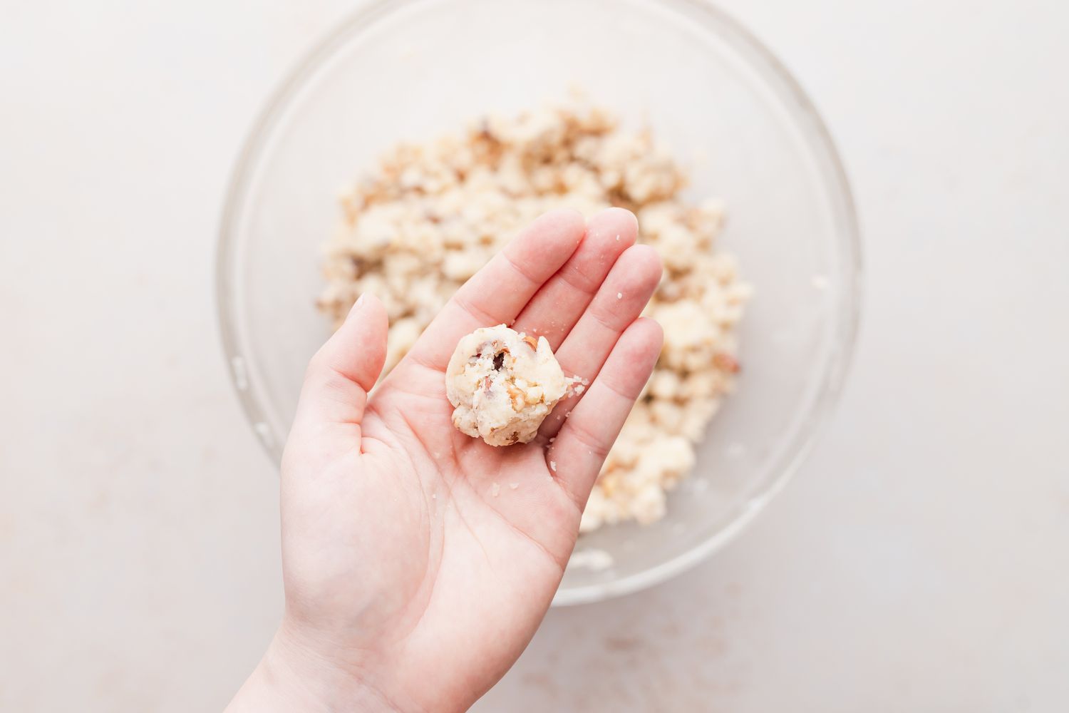 Rolling walnut cookies recipe into a ball.