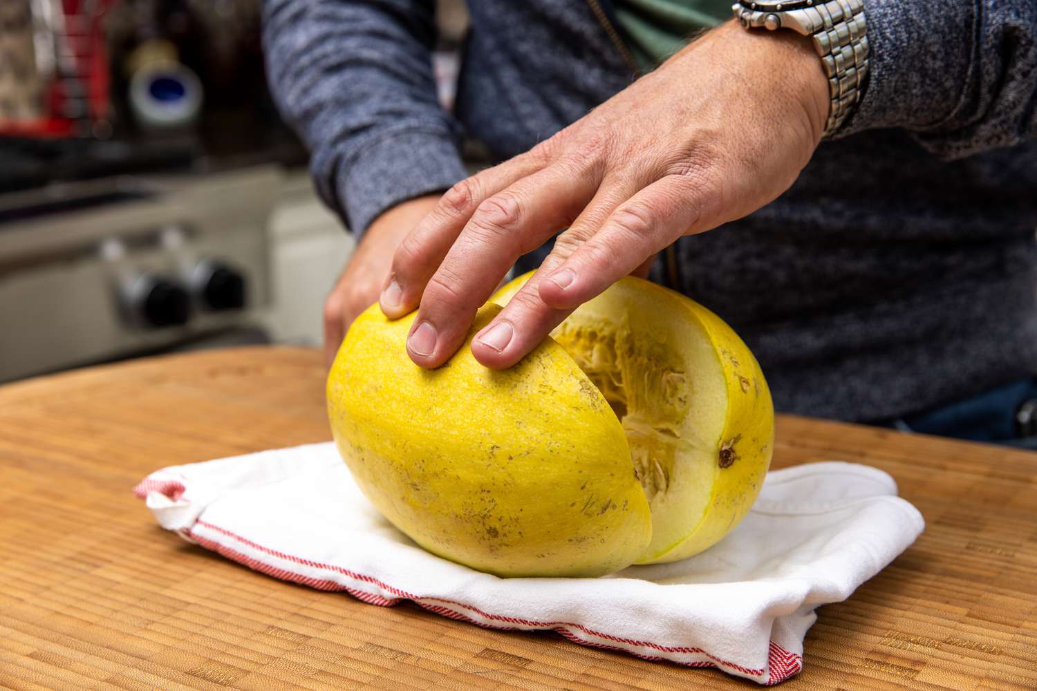 Spaghetti Squash Carefully Cut in Half While Placed on a Folded Kitchen Towel for Spaghetti Squash Soup with Italian Sausage Recipe