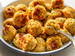 Closeup view of a bowl of 3-ingredient chicken meatballs with a fork on a white tabletop