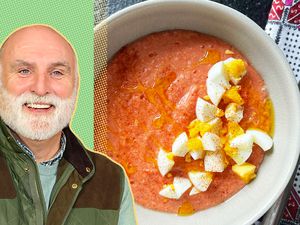 José Andrés alongside a bowl of creamy tomato soup garnished with hard-boiled eggs and spices