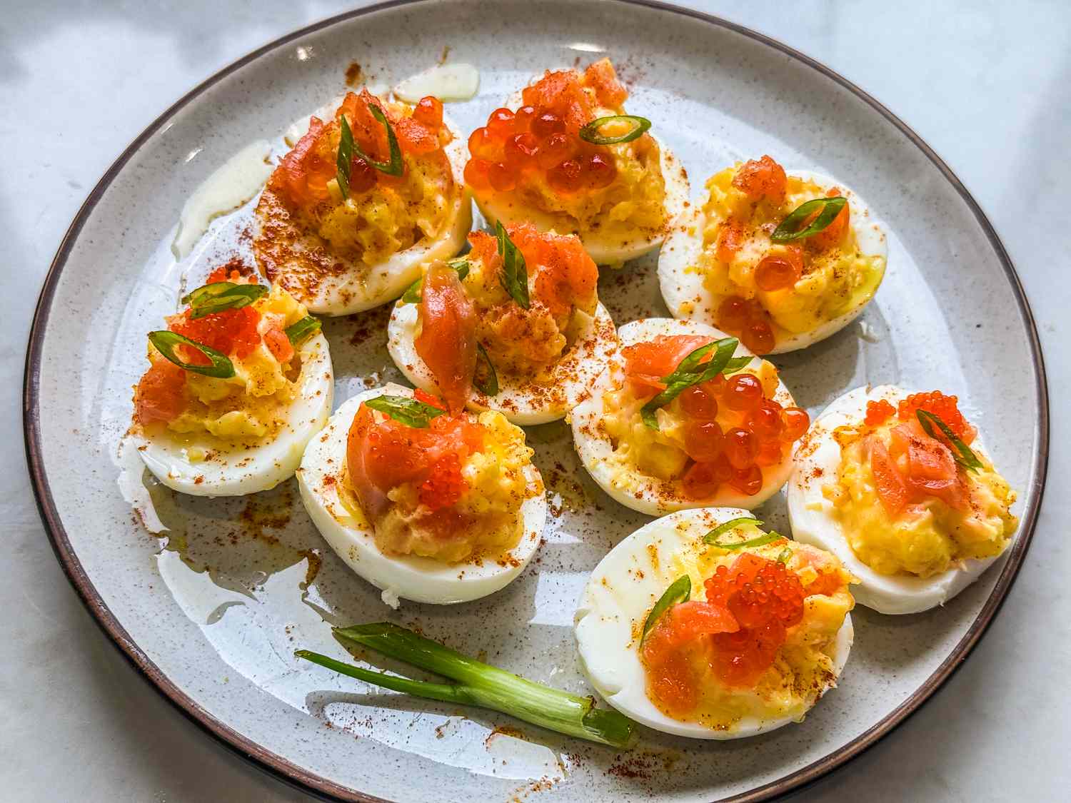 A plate of deviled eggs topped with salmon roe and smoked salmon