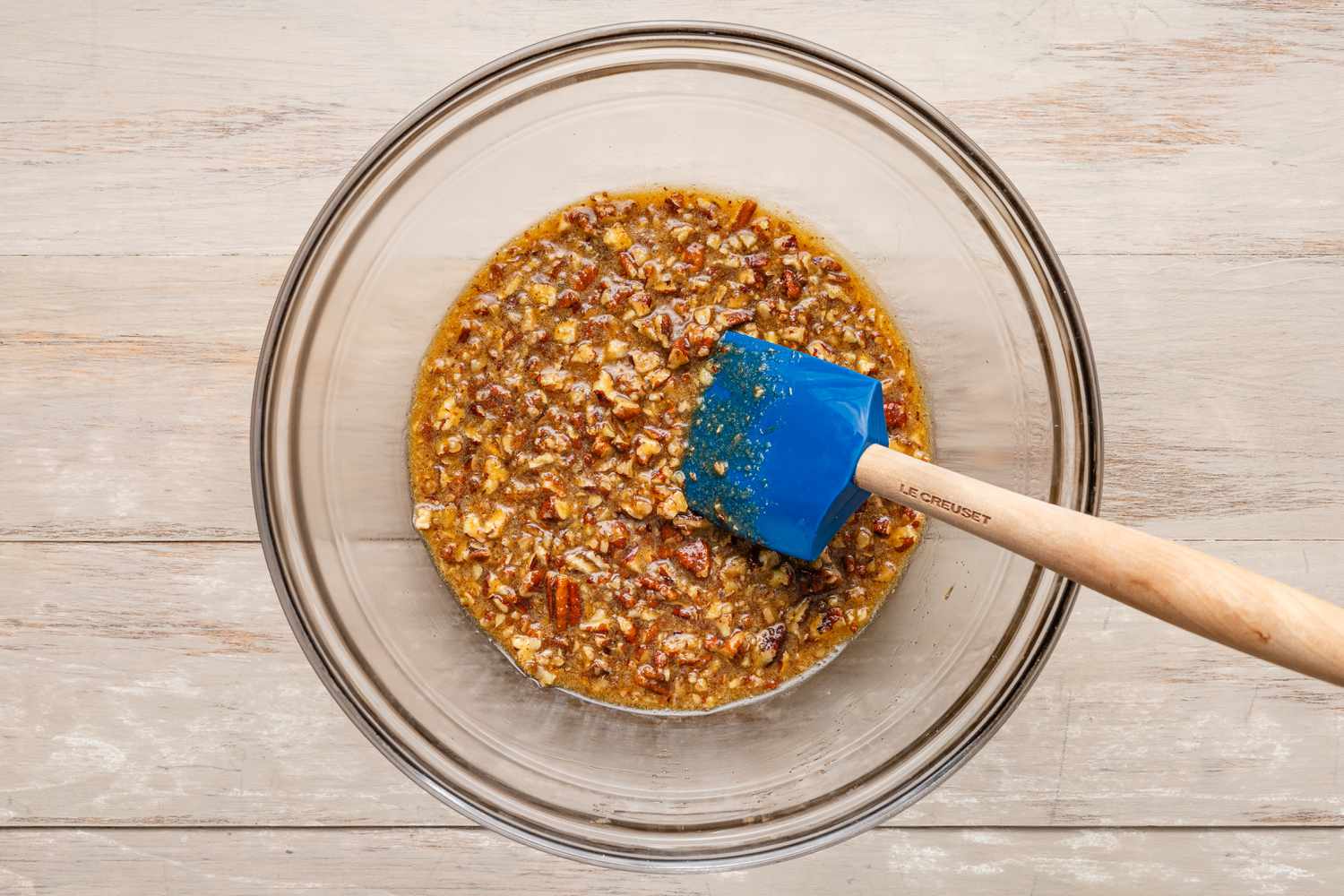 Chopped pecans added to the filling mixture in the bowl with a rubber spatula
