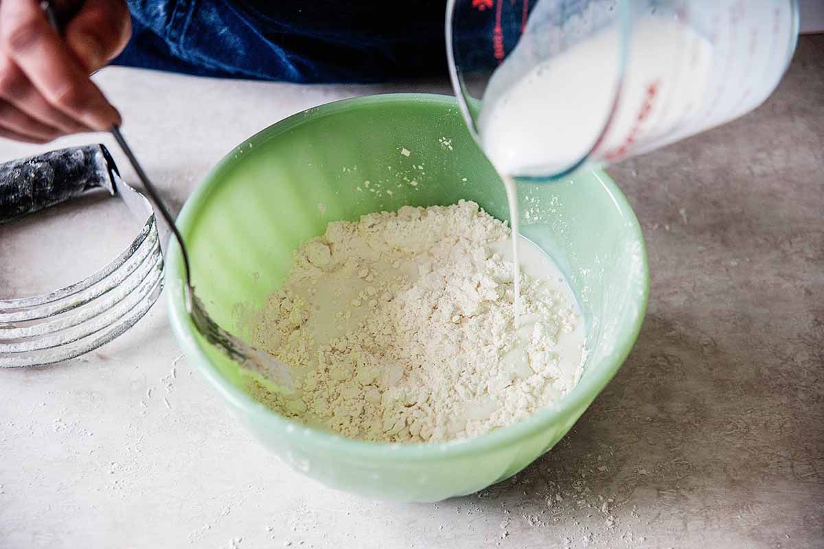 Southern buttermilk biscuits - buttermilk being poured into bowl with flour
