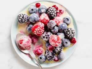 Frozen berries with white chocolate sauce on a plate with a spoon
