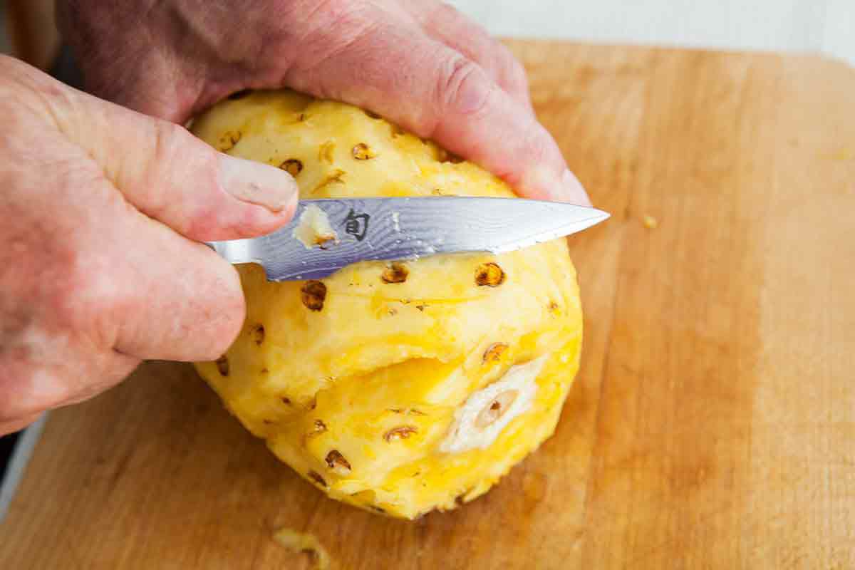 make V trenches with your knife to cut out the eyes in spiral around the pineapple