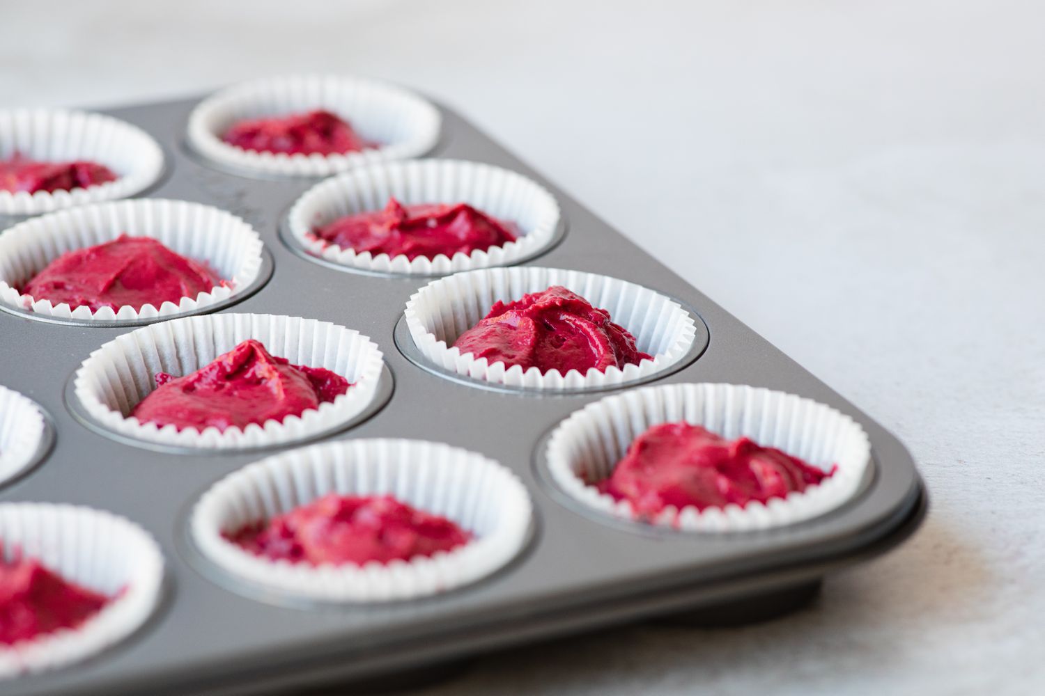 Batter in muffin tins to make best red velvet cake recipe.