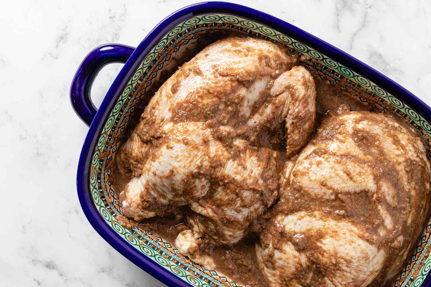 A baking dish of chicken and sauce to show how to make jerk chicken