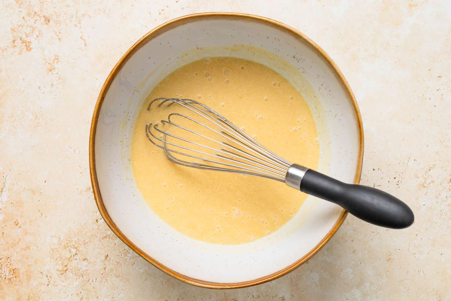 Buttermilk whisked into a bowl of wet ingredients for bran muffins recipe