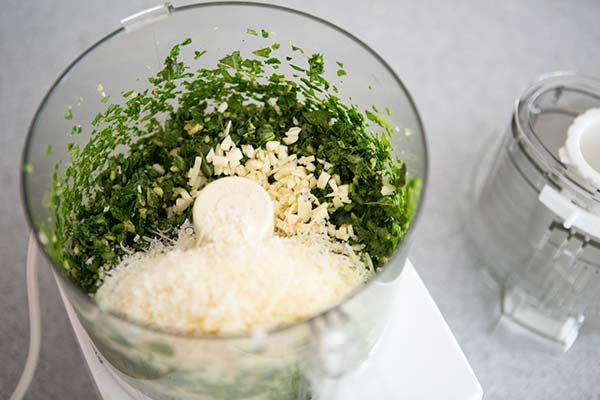 Garlic and cheese being added to the blended basil mixture 