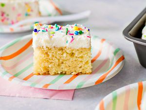 slice of vanilla cake on a paper plate a table with more slices on other paper plates 