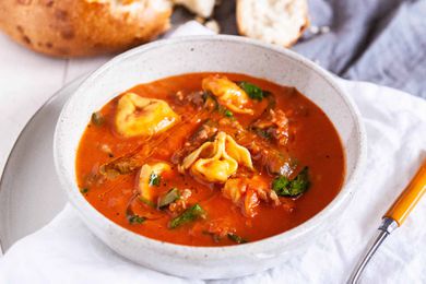 One-Pot Tortellini Soup - white bowl with tomato soup, fresh basil and cheese filled tortellini