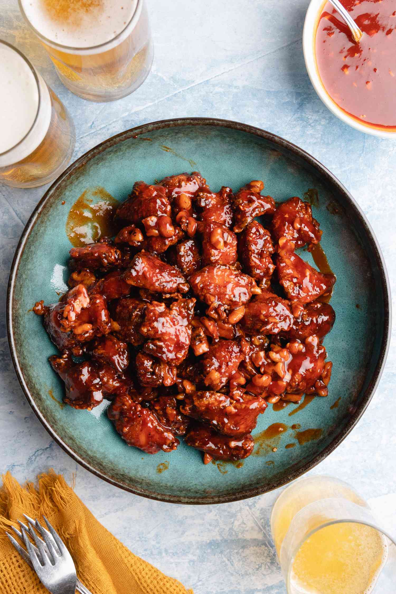 Korean fried chicken on blue platter with beer.