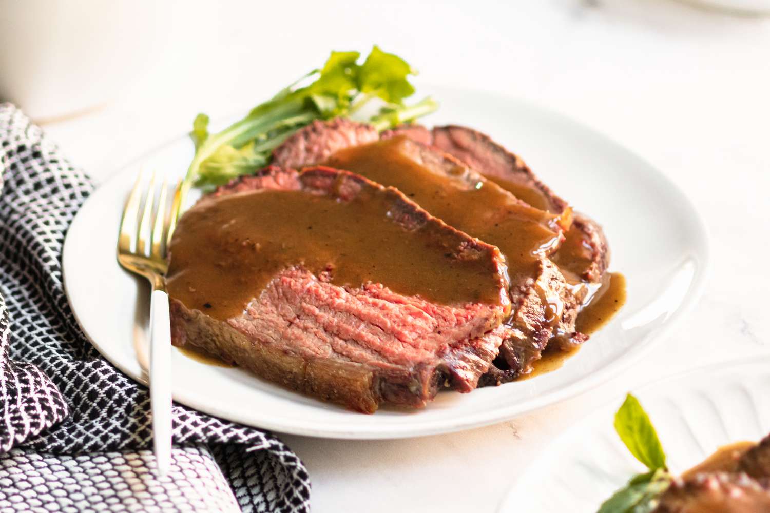 Sliced roast beef with gravy on a white plate
