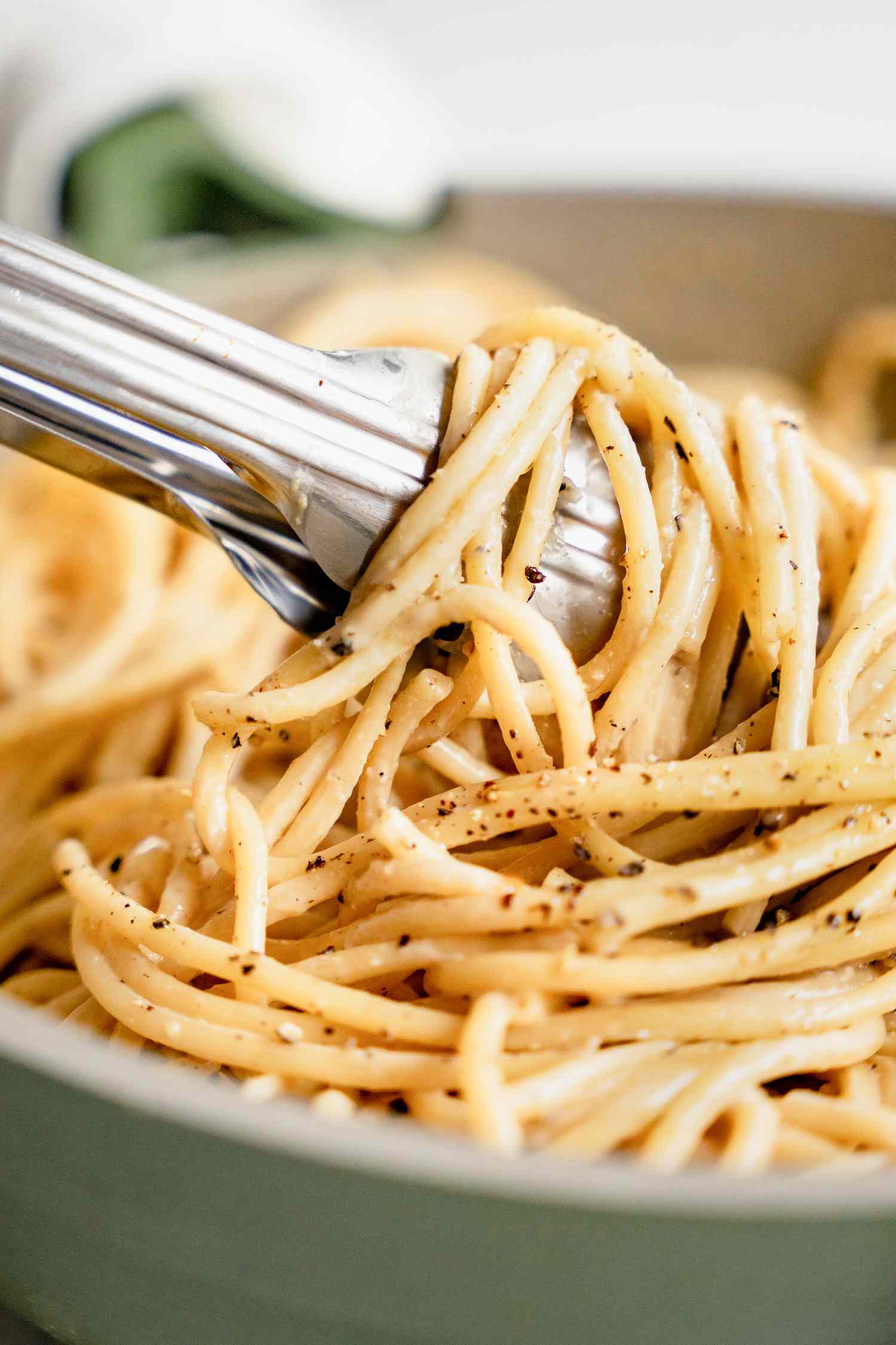Vegan Cacio e Pepe Lifted Using a Pair of Tongs
