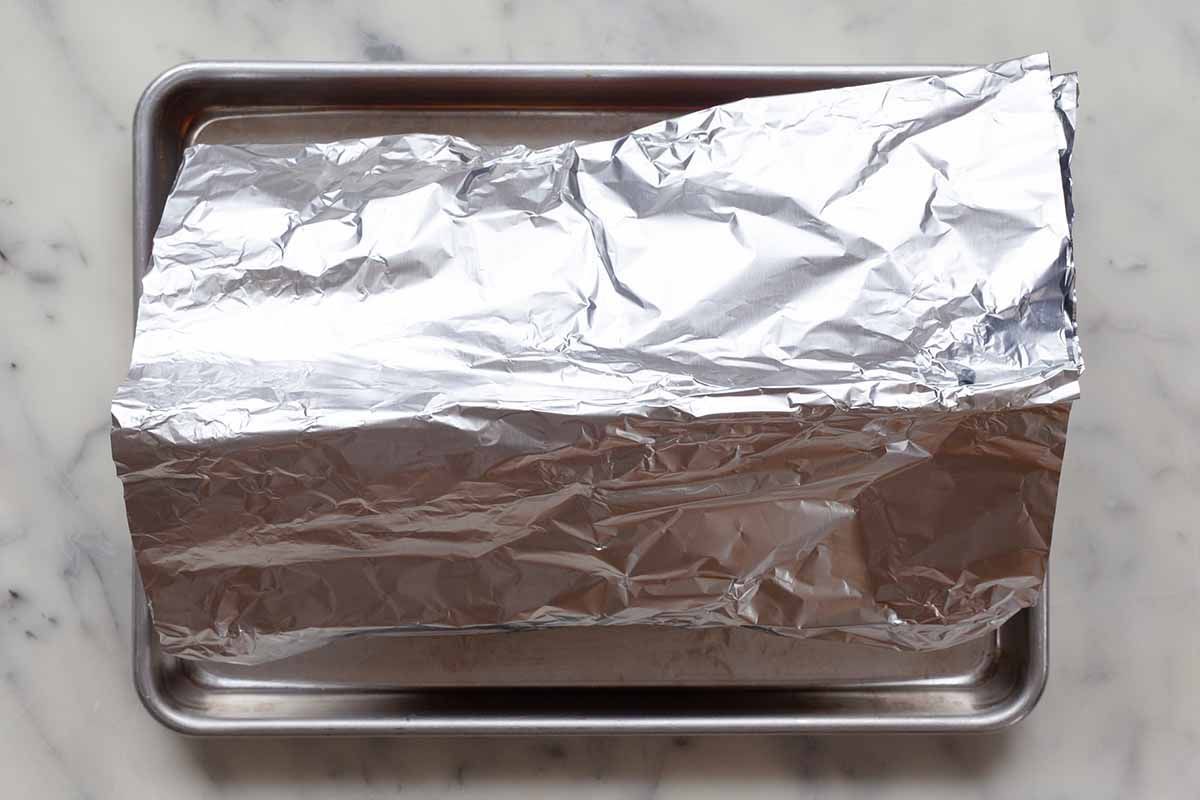 Tented foil covering small batch lasagna on a baking sheet.
