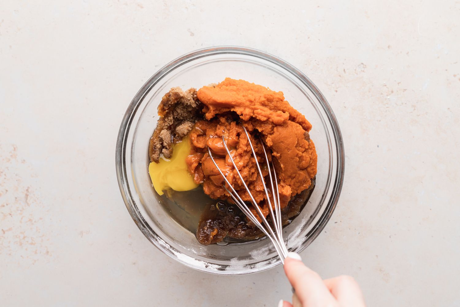 Whisking pumpkin, egg, and sugars to show how to make pumpkin muffins.