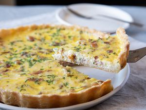 Side view of quiche with a piece being lifted up.