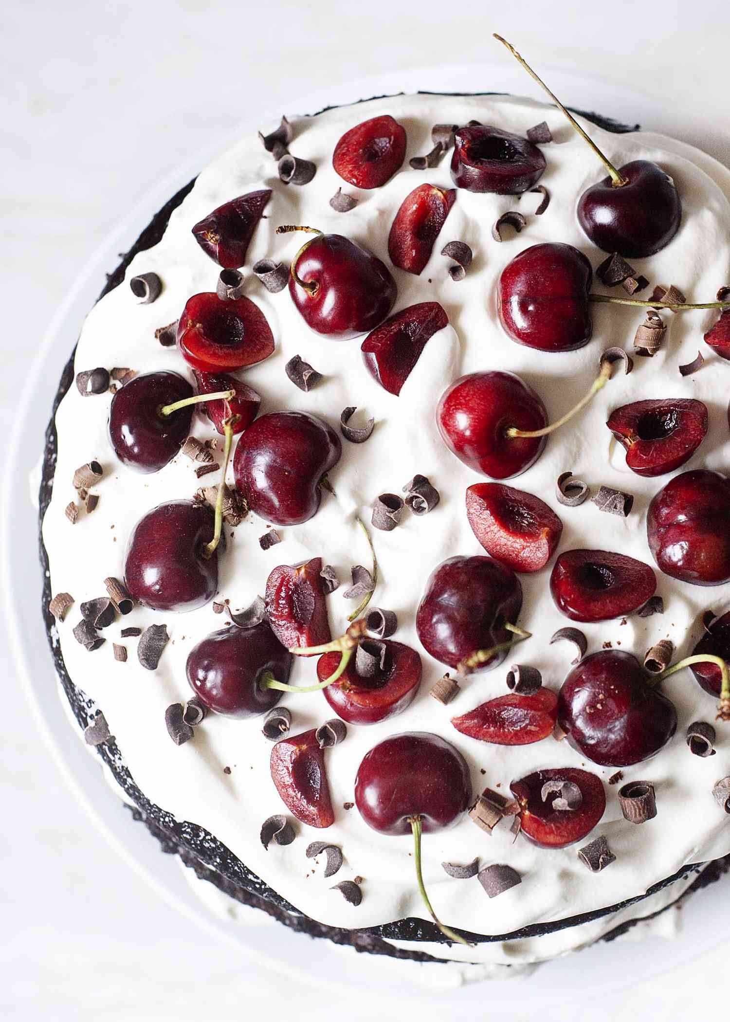 The top of a Cherry Chocolate Cake with Whipped Cream topped with fresh cherries and chocolate.