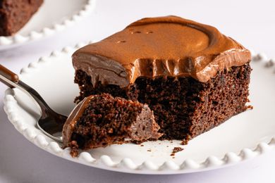 Angled view of a slice of Easy Brooklyn Blackout Cake on a white plate with a fork holding a bite removed from the slice