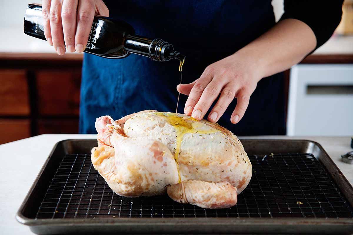 How to Roast a Whole Chicken - pouring olive oil over chicken