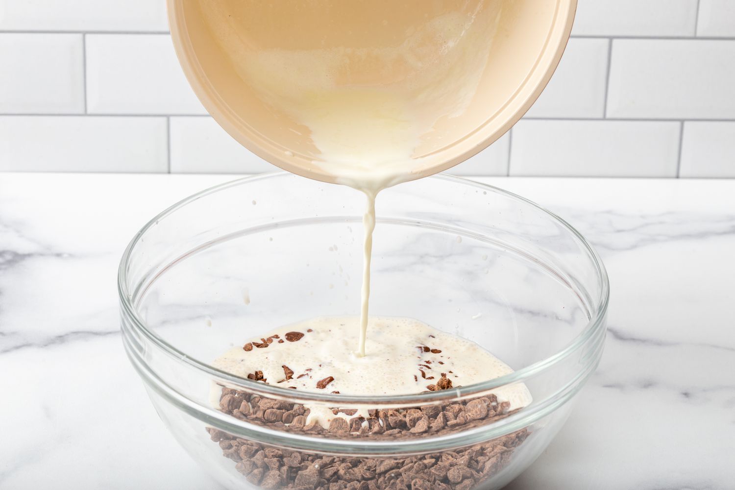 Pouring warm cream over chocolate chips for a truffle recipe.