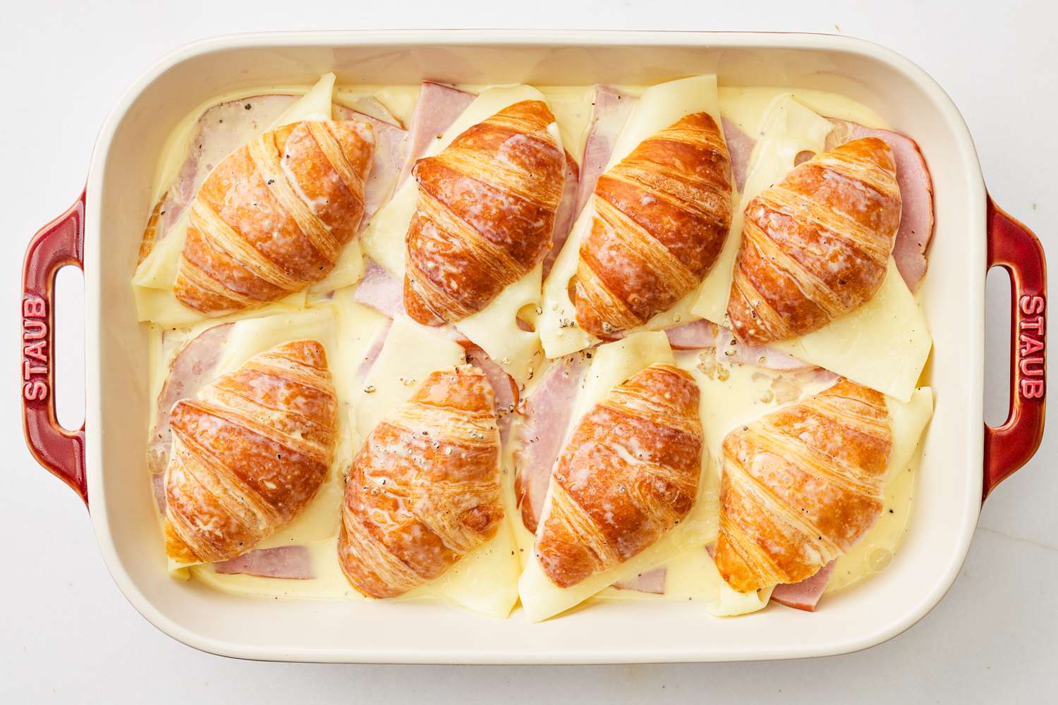 Egg mixture poured into the casserole dish with monte cristo sandwiches