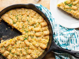 Tater Tot Breakfast Casserole in a cast iron skillet, one slice removed and placed on a dish