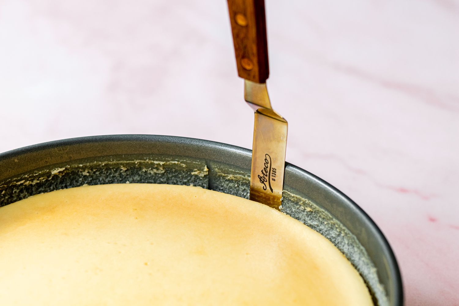 Running an offset spatula around the springform pan to remove the cheesecake