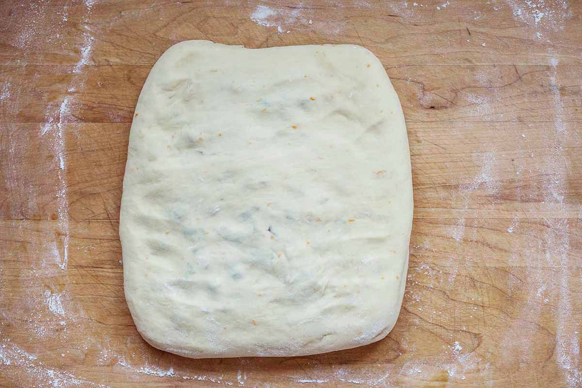 A flattened square of panettone dough on a cutting board 