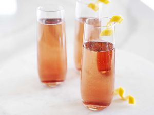 Side view of kir royale in three tall and slender glasses on a white background