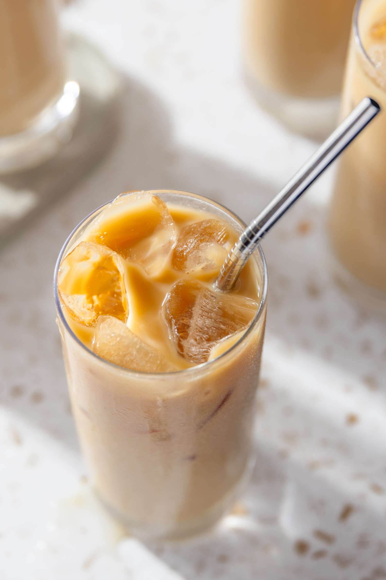 Overhead Shot of a Glass of Thai Iced Tea With a Straw, and in the Surroundings, More Glasses of Thai Iced Tea