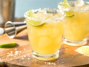 Margaritas on a wooden board with lime wedges and salt