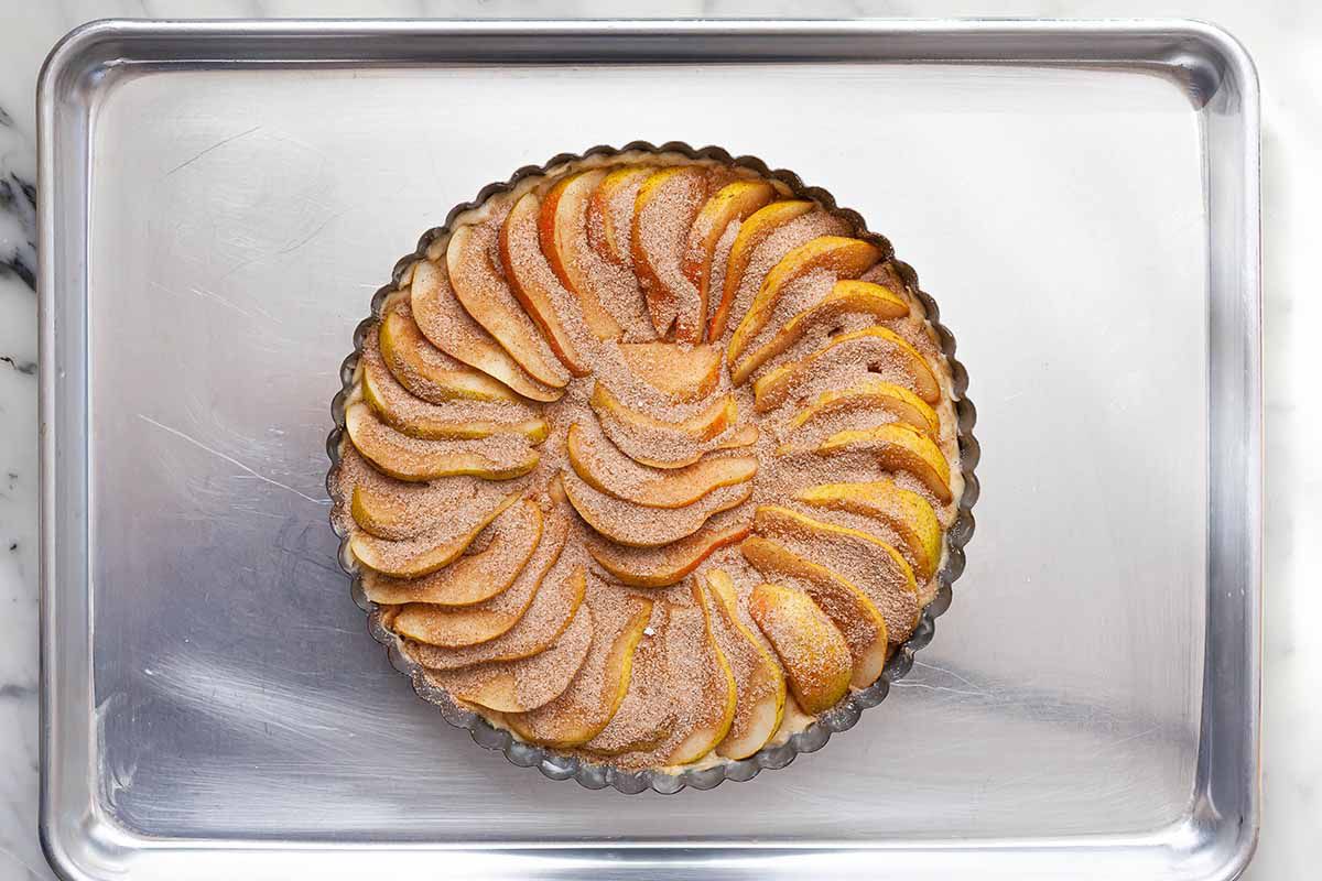 Pear coffee cake in a fluted tart tin dusted with cinnamon and sugar