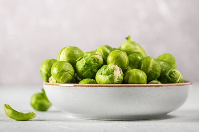 A withe bowl with whole raw brussels sporuts
