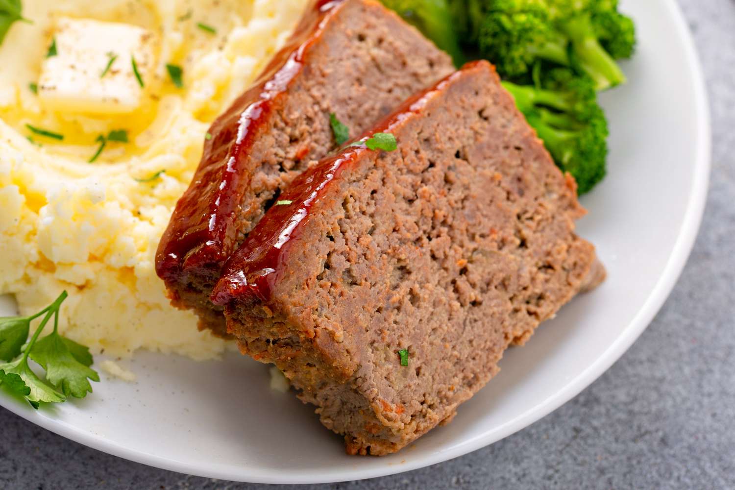 Two slices of meatloaf on a plate with mashed potatoes