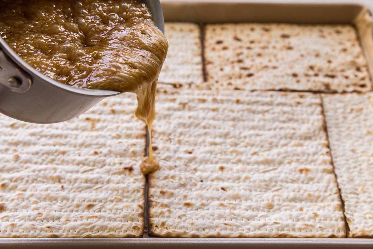 How to Make Matzo Toffee - hot toffee being poured over matzo crackers