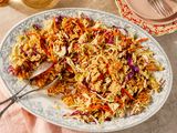 Overhead view of a decorative serving platter of crunchy ramen salad with serving scoops