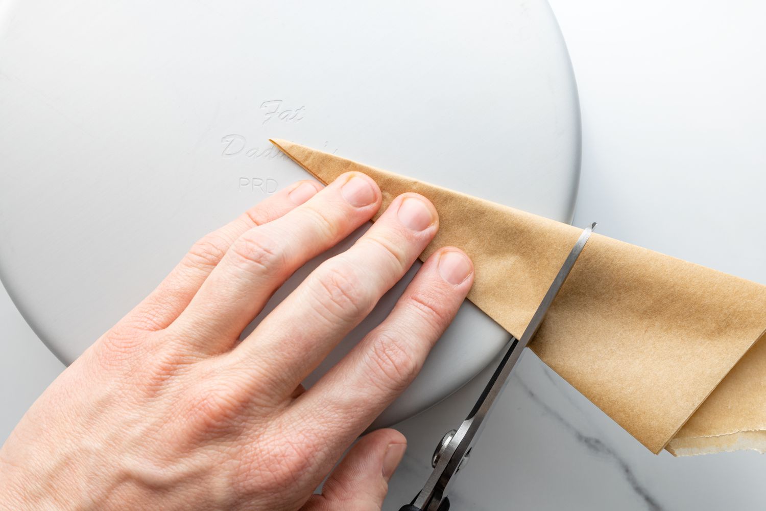 Trimming a parchment round with scissors to line a cake pan