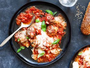 Mozzarella-stuffed meatballs with sauce on a plate with a spoon and bread on the side