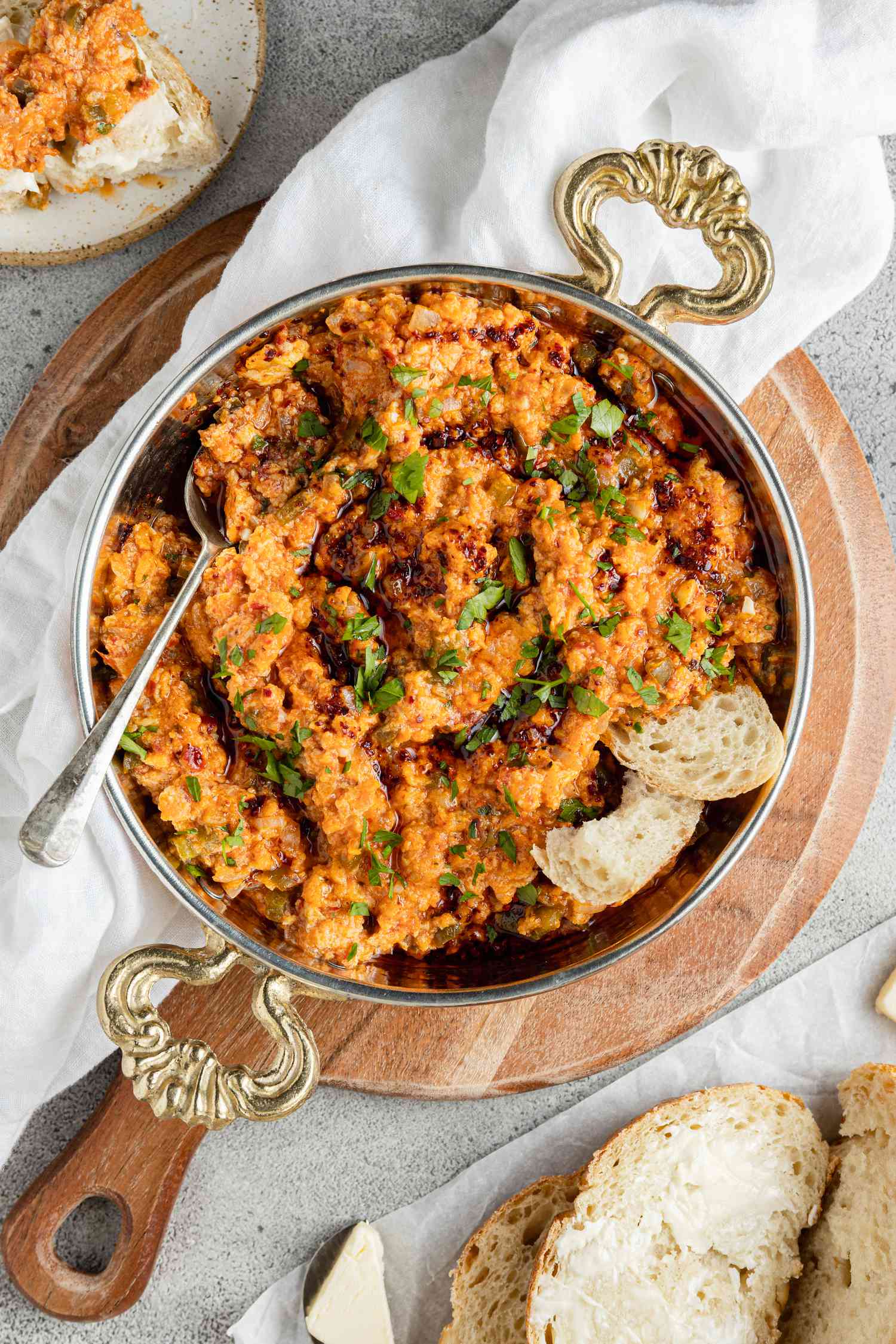 Menemen (Turkish Scrambled Eggs and Tomatoes) in a Pot with a Spoon, Surrounded by Some Slices of Bread and a Plate