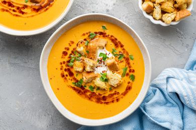 Overhead view of a bowl of creamy soup garnished with croutons and oil