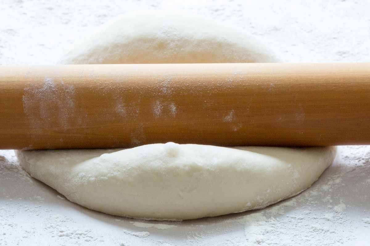 Roll out the pizza dough for the stromboli with a rolling pin