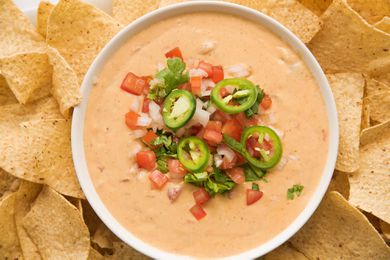 Get ready for game day with a bowl of ceamy queso dip topped with pico de gallo and surrounded by tortilla chips