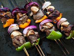 Shish Kabobs on wooden skewers with onions, bell peppers, and mushrooms, ready to eat