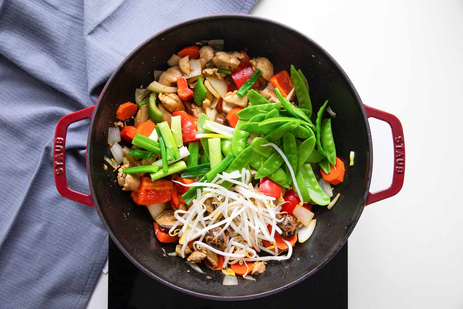 Snow Peas, Mung Bean Sprouts, and Spring Onions in a Wok on a Portable Burner, and Next to It, a Blue Kitchen Towel for Chop Suey Recipe