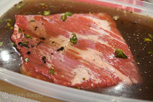 A cut of beef submerged in a marinade 