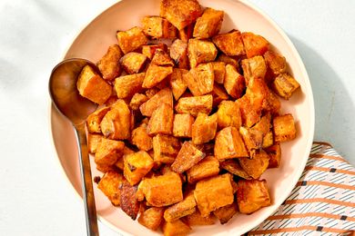 Overhead view of a bowl with cubes of roasted sweet potato along with a metal spoon