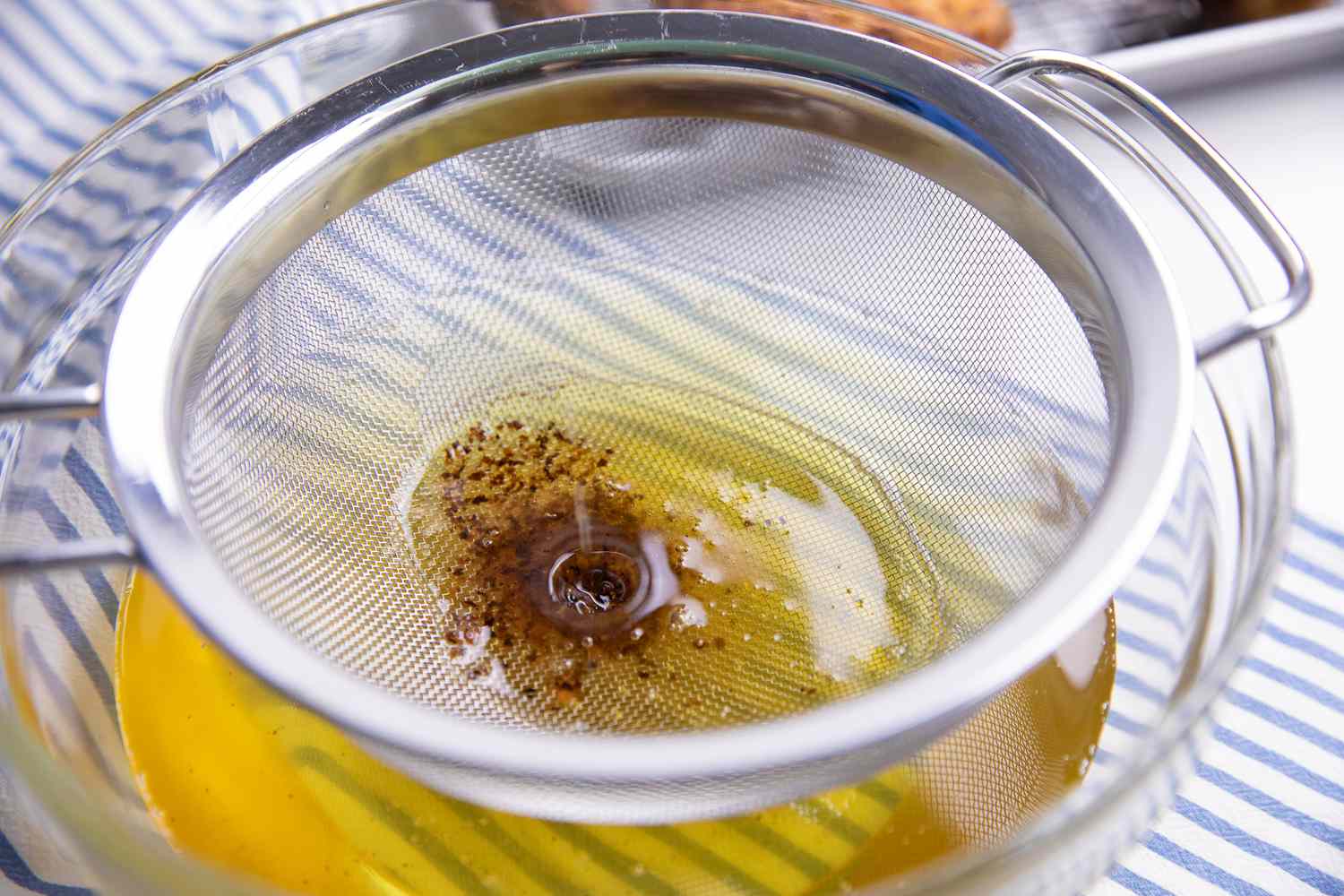 Frying Oil Poured into a Sieve to Separate Oil from Leftover Fried Bits for How to Deep Fry