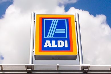 An Aldi sign with clouds and a blue sky in the background