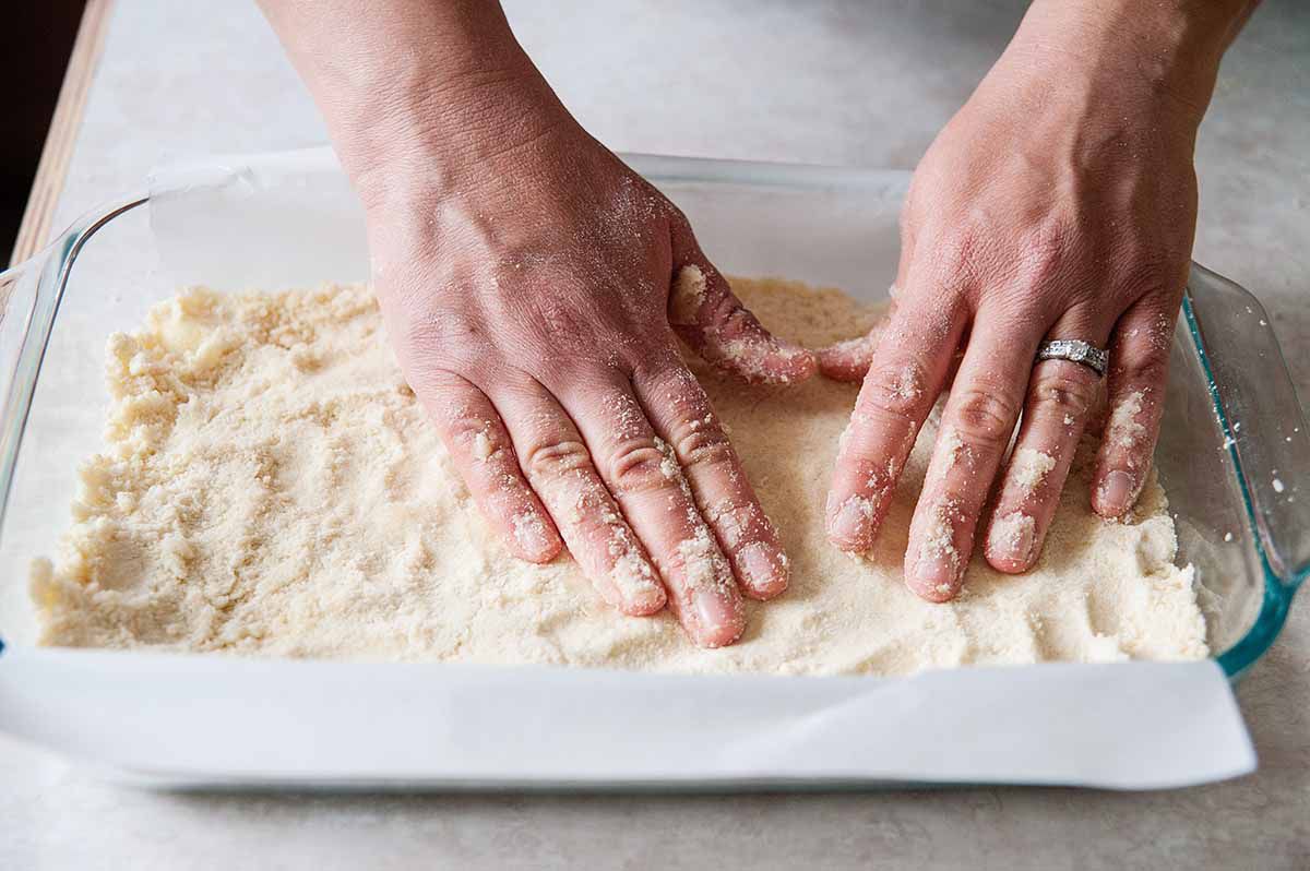 Lemon Bar Recipe - hands pressing shortbraed into pan